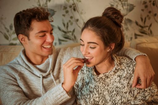 Happy man feeding woman with sweets